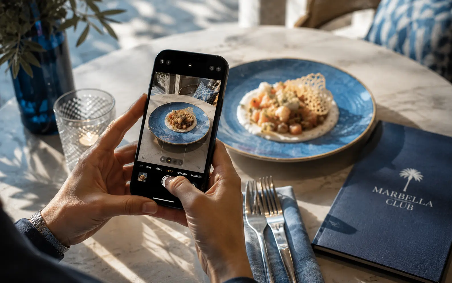 Social media content session: hands photographing a dish from a Marbella restaurant with a smartphone